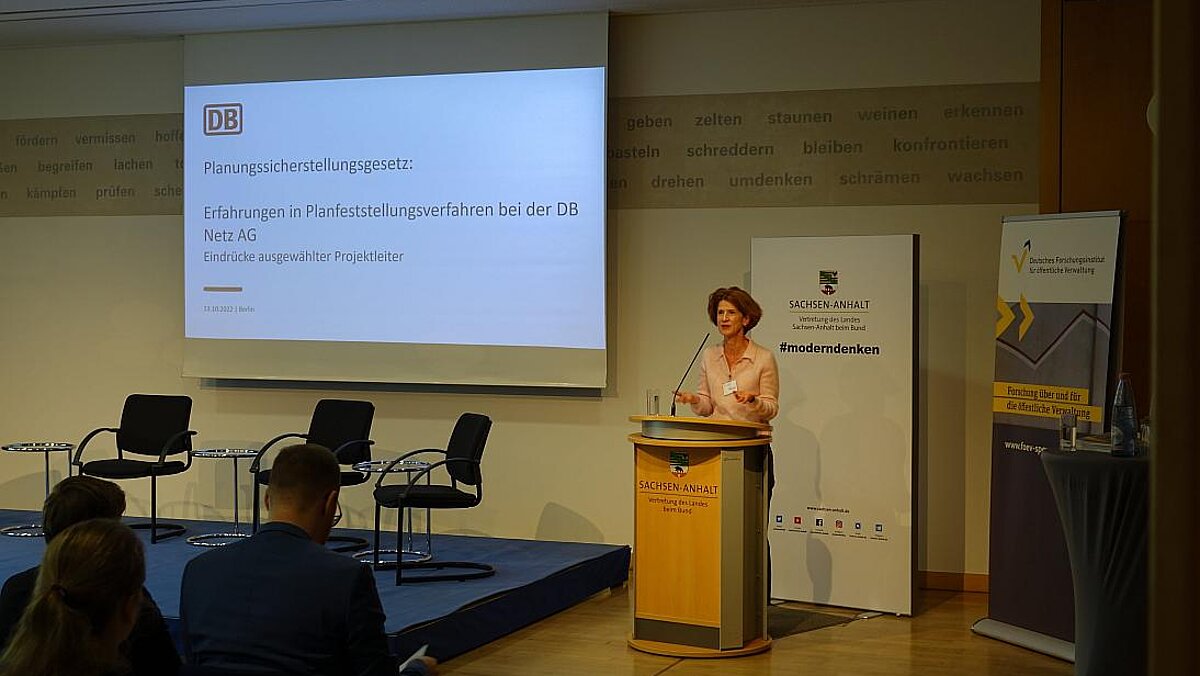Woman at the lectern, a screen on the left