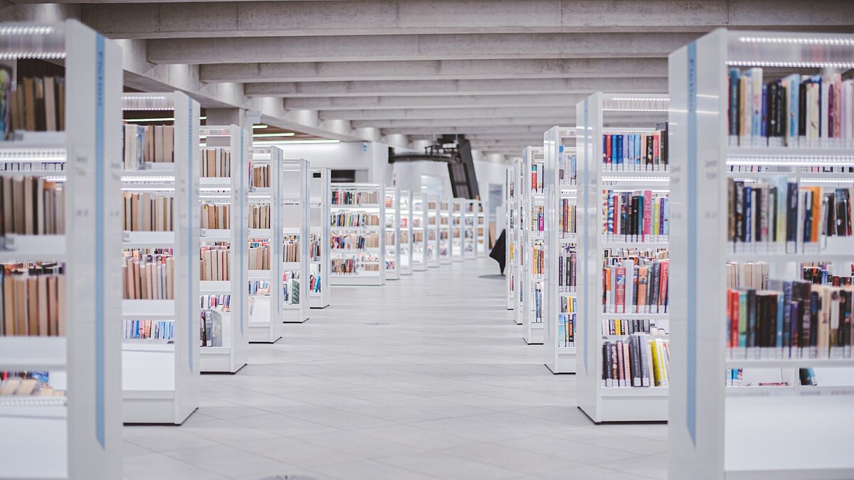 Eine hellerleuchtete, moderne Bibliothek mit weißen Regalen.