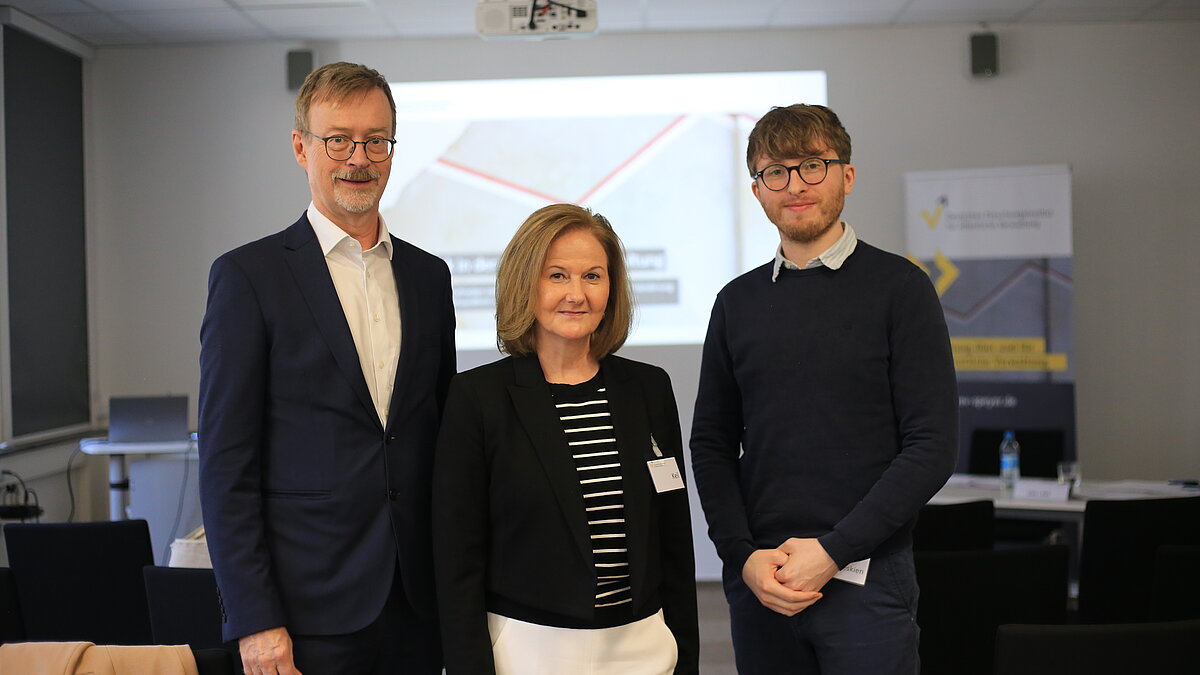 Gruppenbild mit drei Personen im Veranstaltungsraum.