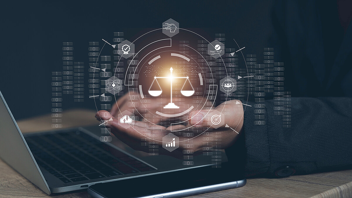 Tisch mit Laptop und Smartphone, Hand eines Mannes unter digitaler Holografie mit binären Zahlencodes, Icons für künstliche Intelligenz und der Waage von Justitia