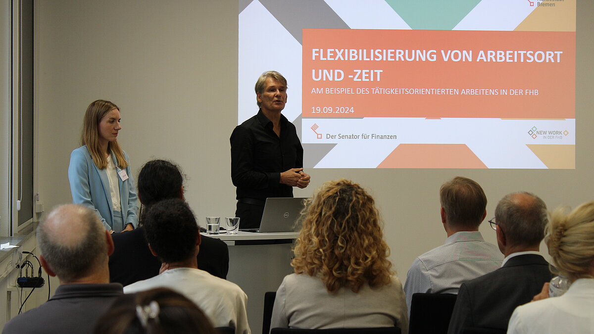 Zwei Personen präsentieren ihre Ergebnisse mittels einer Power-Point-Präsentation.